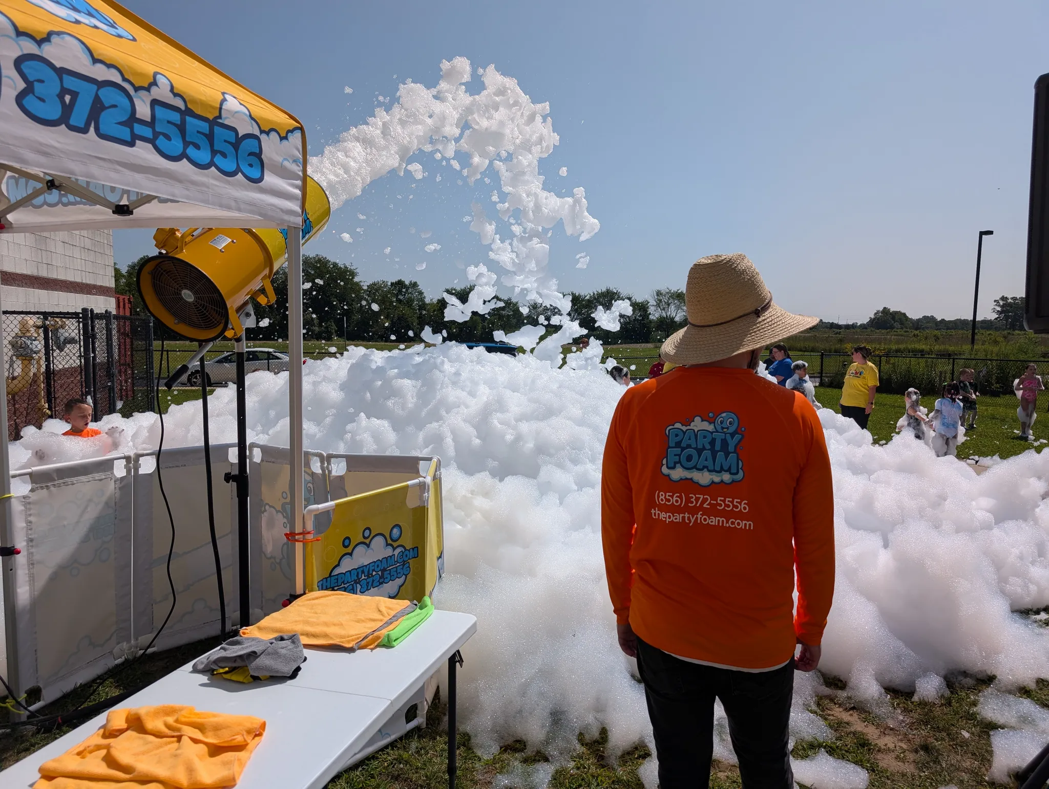 Party Foam operator in branded orange shirt professionally overseeing a foam party while kids play safely
